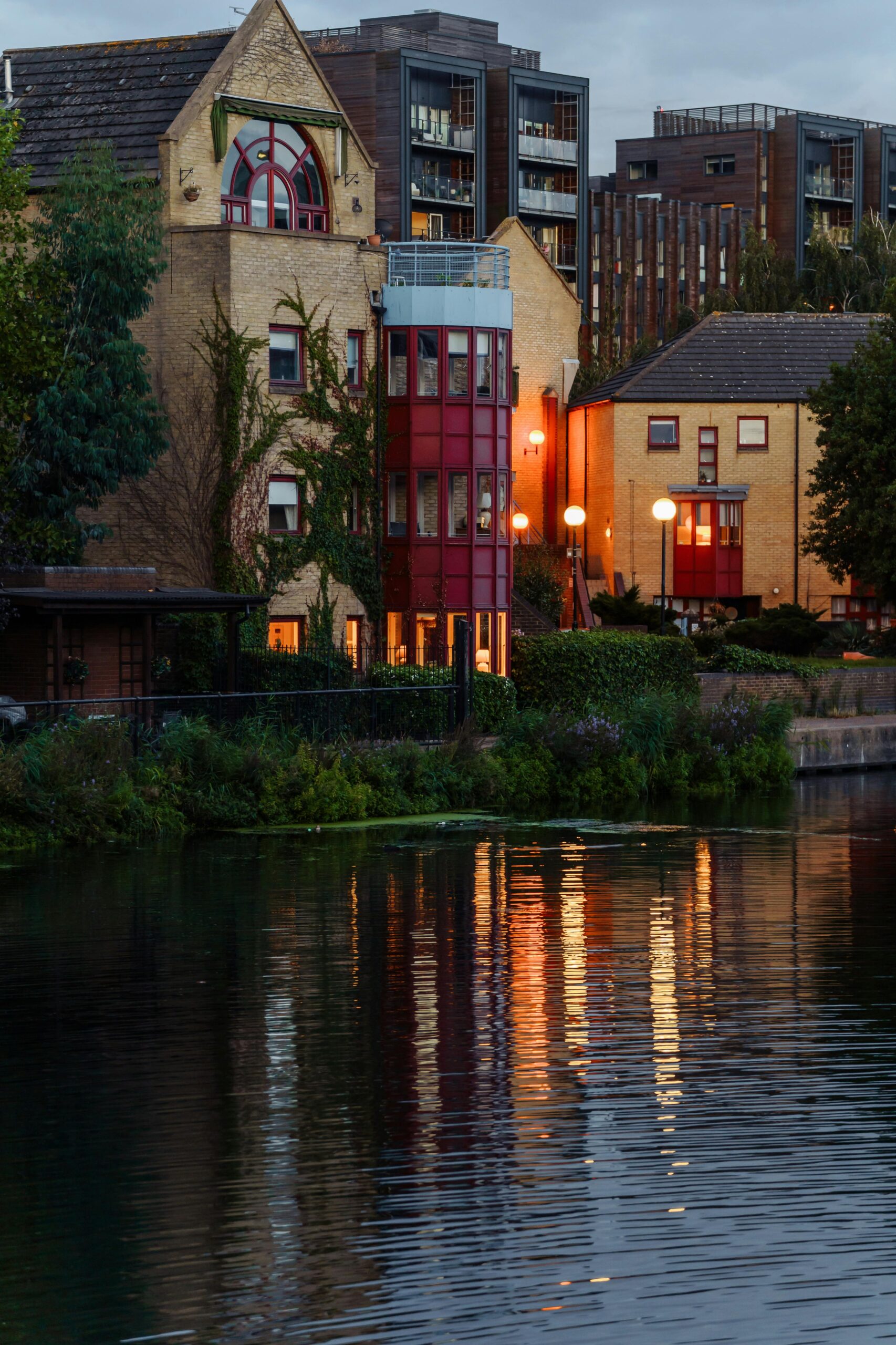 Evening view of illuminated riverside buildings reflecting in a serene water canal in London.